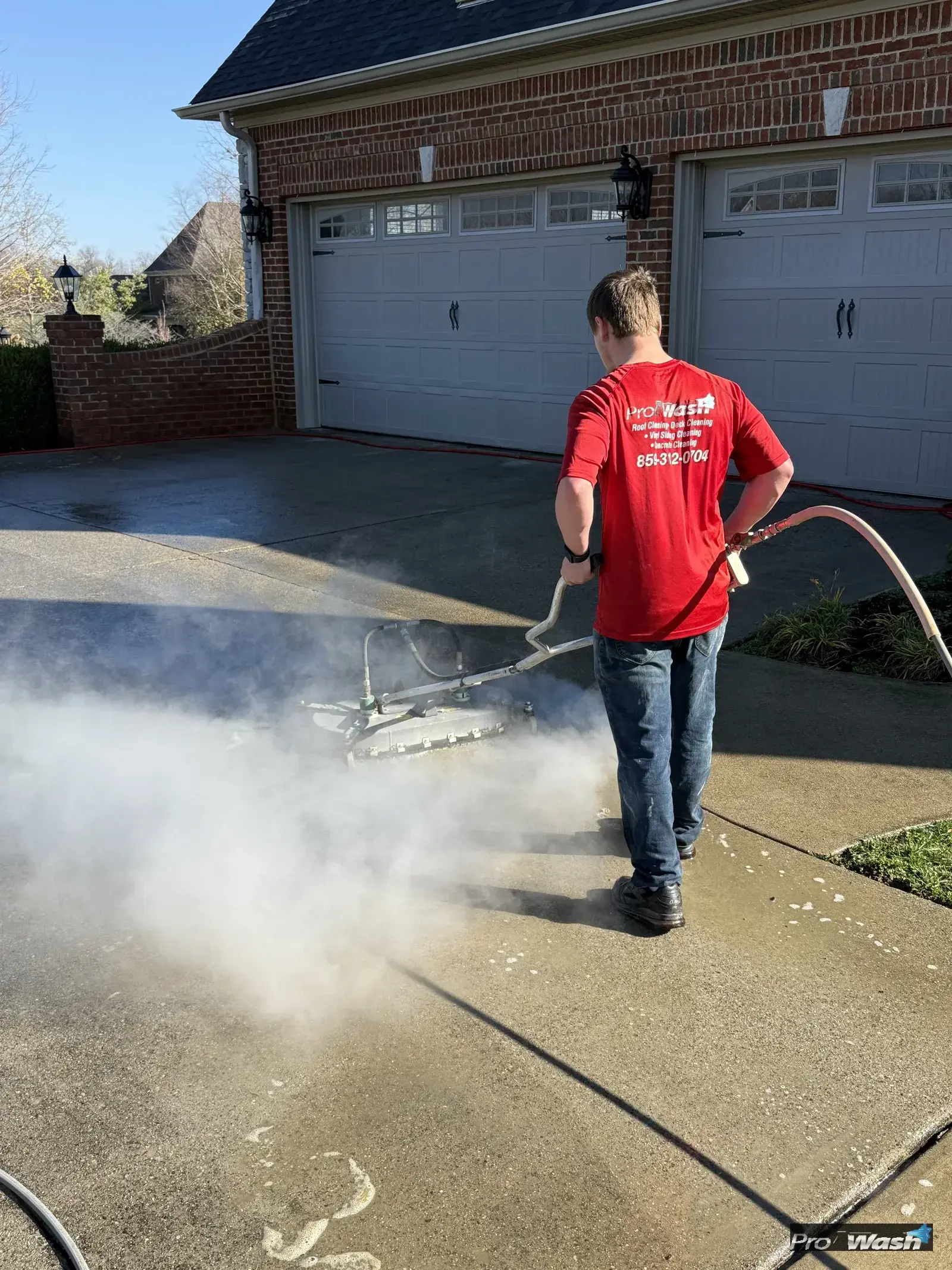A flat surface cleaner being used on concrete by an Inman ProWash technician.
